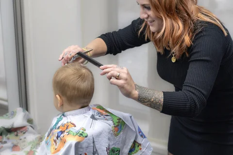 Kinderhaarschnitt im Salon mit buntem Umhang.